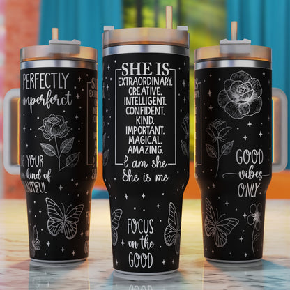 Three black tumblers with motivational quotes and designs on a wooden surface.
